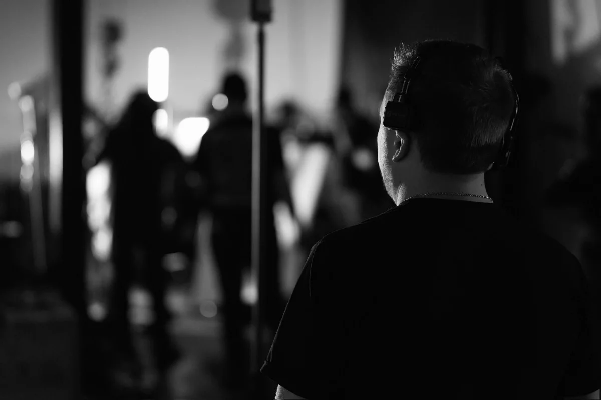 Josh Taube on set, wearing headphones, watching a scene being filmed